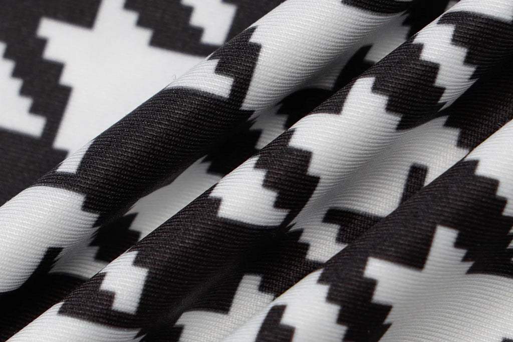Houndstooth print fabric in black and white, featuring a smooth texture and a vibrant, bold pattern.