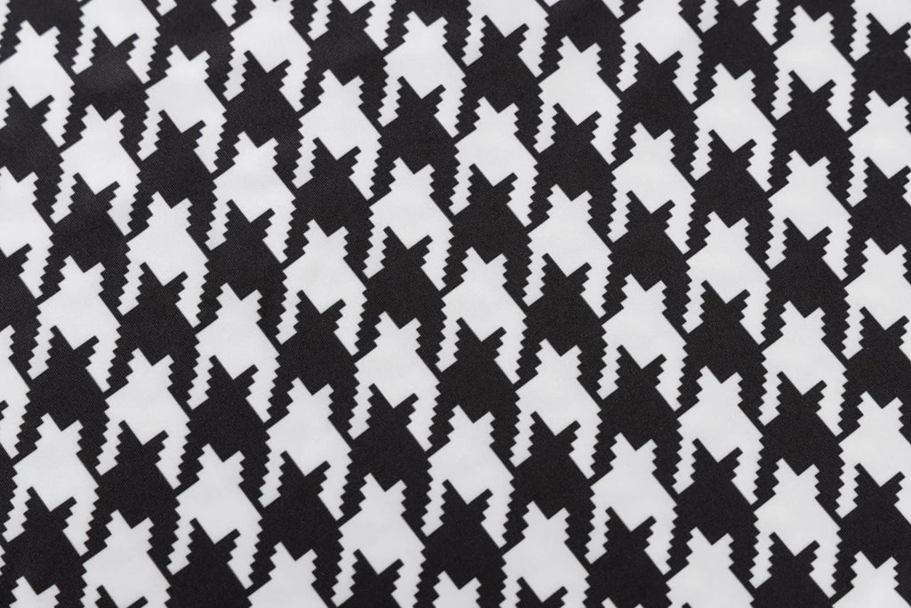 Houndstooth print fabric in black and white, featuring a knit texture and a hollow-out design.