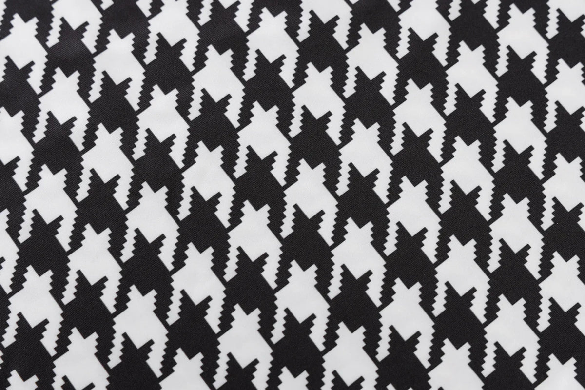Houndstooth print fabric in black and white, featuring a knit texture and a hollow-out design.