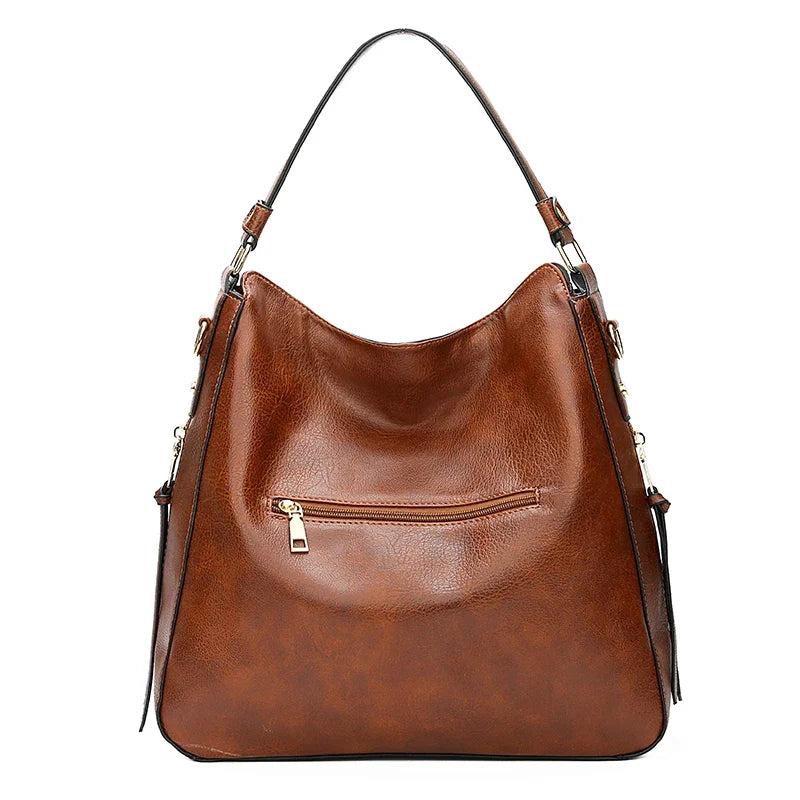 Brown faux leather hobo bag with a single strap, featuring a front zipper pocket and a soft, casual design.