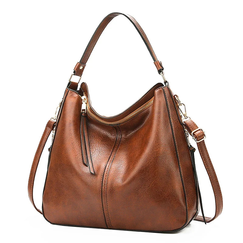 Brown faux leather hobo bag with a single shoulder strap and a zippered top, featuring a soft texture and casual style.