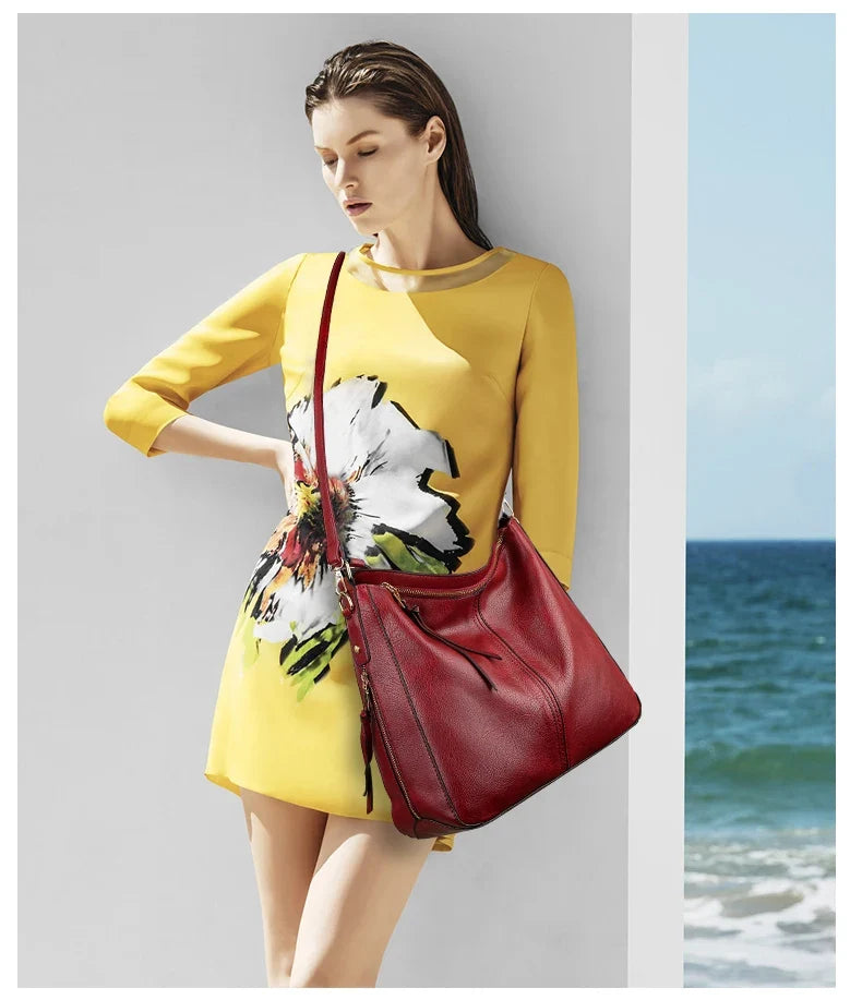 Red faux leather hobo bag with a single shoulder strap, worn with a yellow floral dress against a beach backdrop.