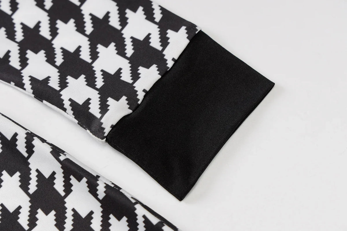 Houndstooth print fabric featuring black and white patterns with solid black cuffs. Perfect for stylish layering.