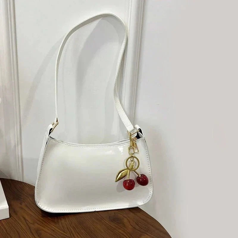 Women's pure leather cherry pendant handbag by TrendLux Wear, solid color with a stylish cherry-shaped pendant detail.