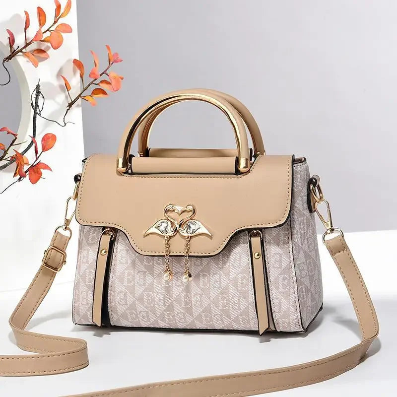 Light beige handbag with a structured design, featuring a flap and gold-tone heart detail. It includes a detachable shoulder strap.