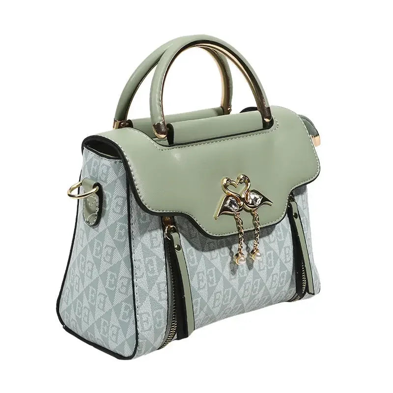 Versatile ladies' handbag in pastel green with embossed design, gold accents, and dual handles; features a solid pattern.