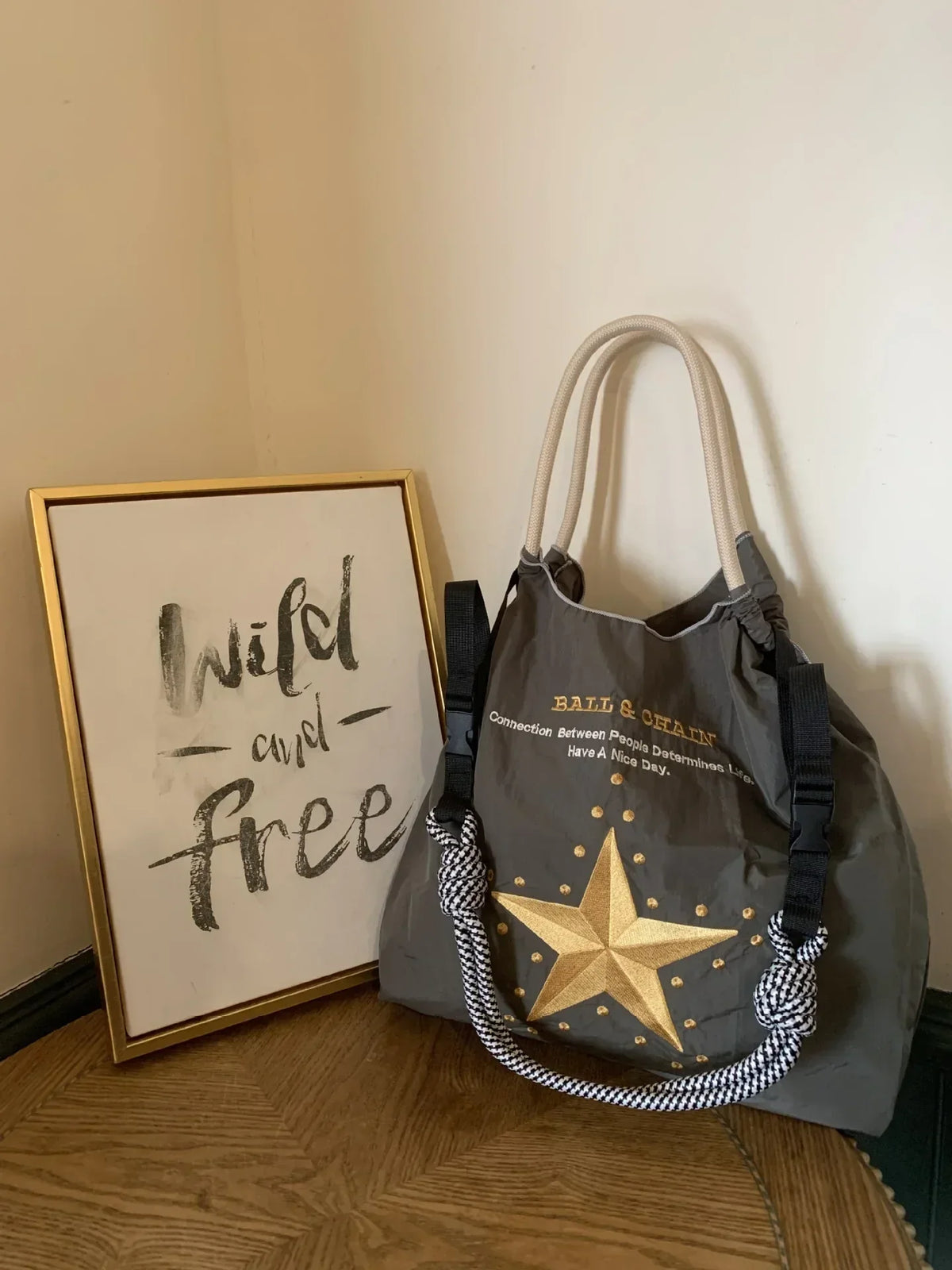 Lightweight gray nylon tote bag with a gold star design, featuring dual handles and decorative strap accents.
