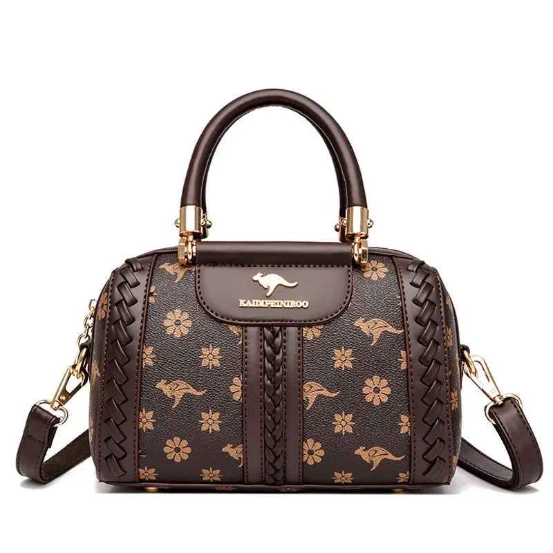 Brown semi-woven shoulder handbag featuring gold floral patterns and kangaroo logo, with a single handle and adjustable strap.