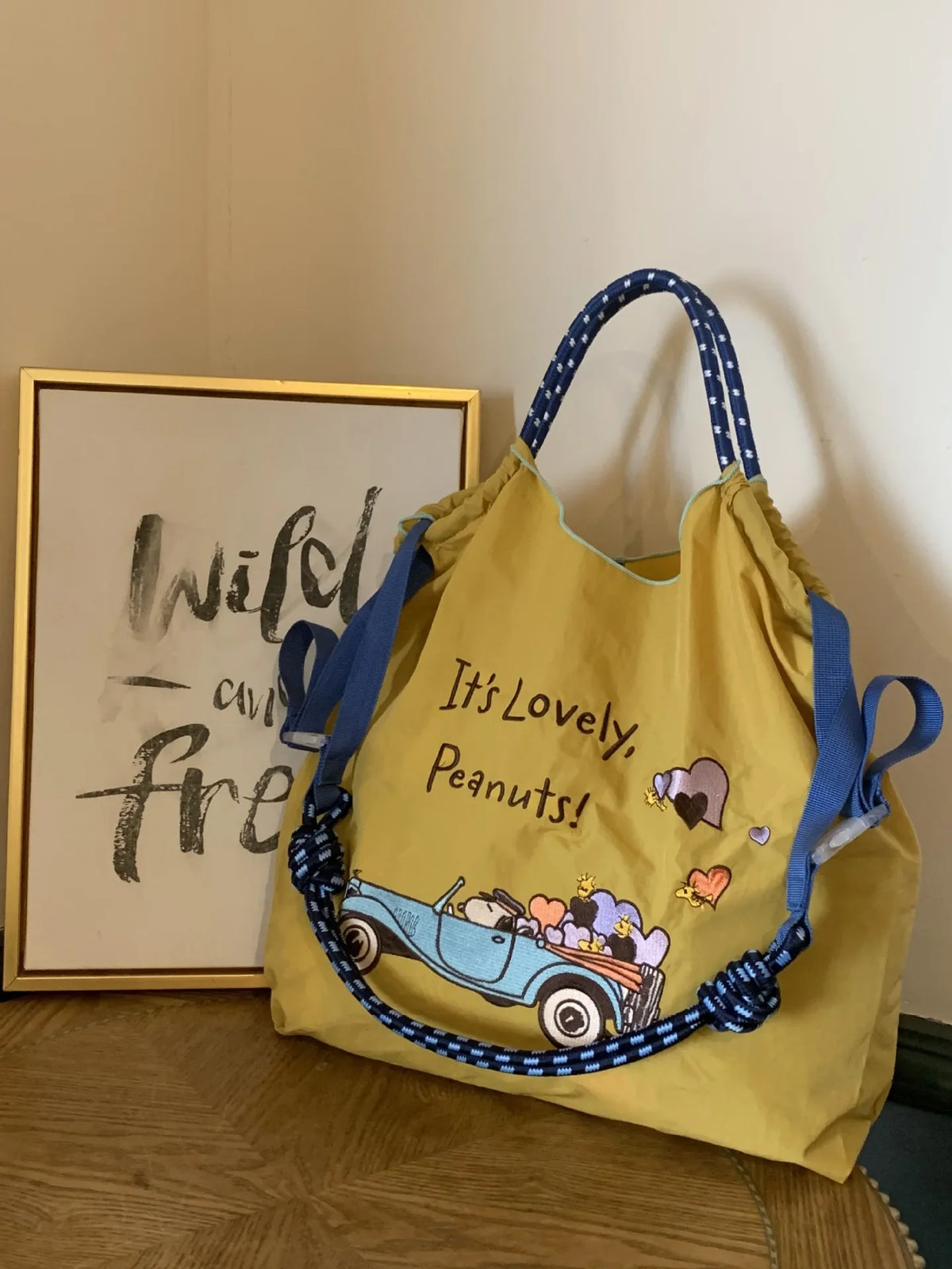 Large yellow nylon tote bag with blue and white straps, featuring an embroidered design of a car and hearts.