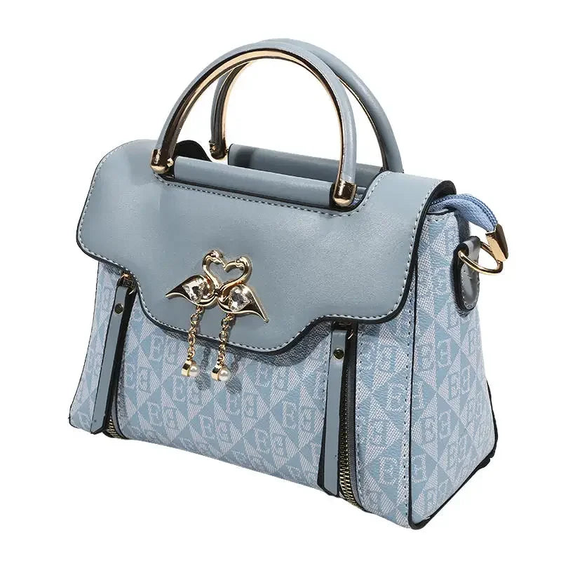 Light blue women's handbag with embossed pattern, gold-tone clasp, and dual top handles. Casual shoulder/crossbody style.