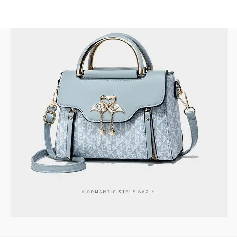 Embossed light blue handbag with gold accents, featuring a top handle and adjustable crossbody strap.