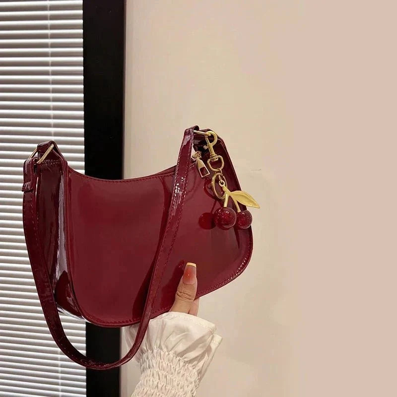 Women's pure leather cherry pendant handbag by TrendLux Wear, solid color with a stylish cherry-shaped pendant detail.
