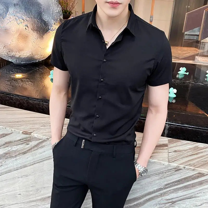 Short-sleeve black shirt with a square collar, buttoned, worn tucked into black trousers by a model.