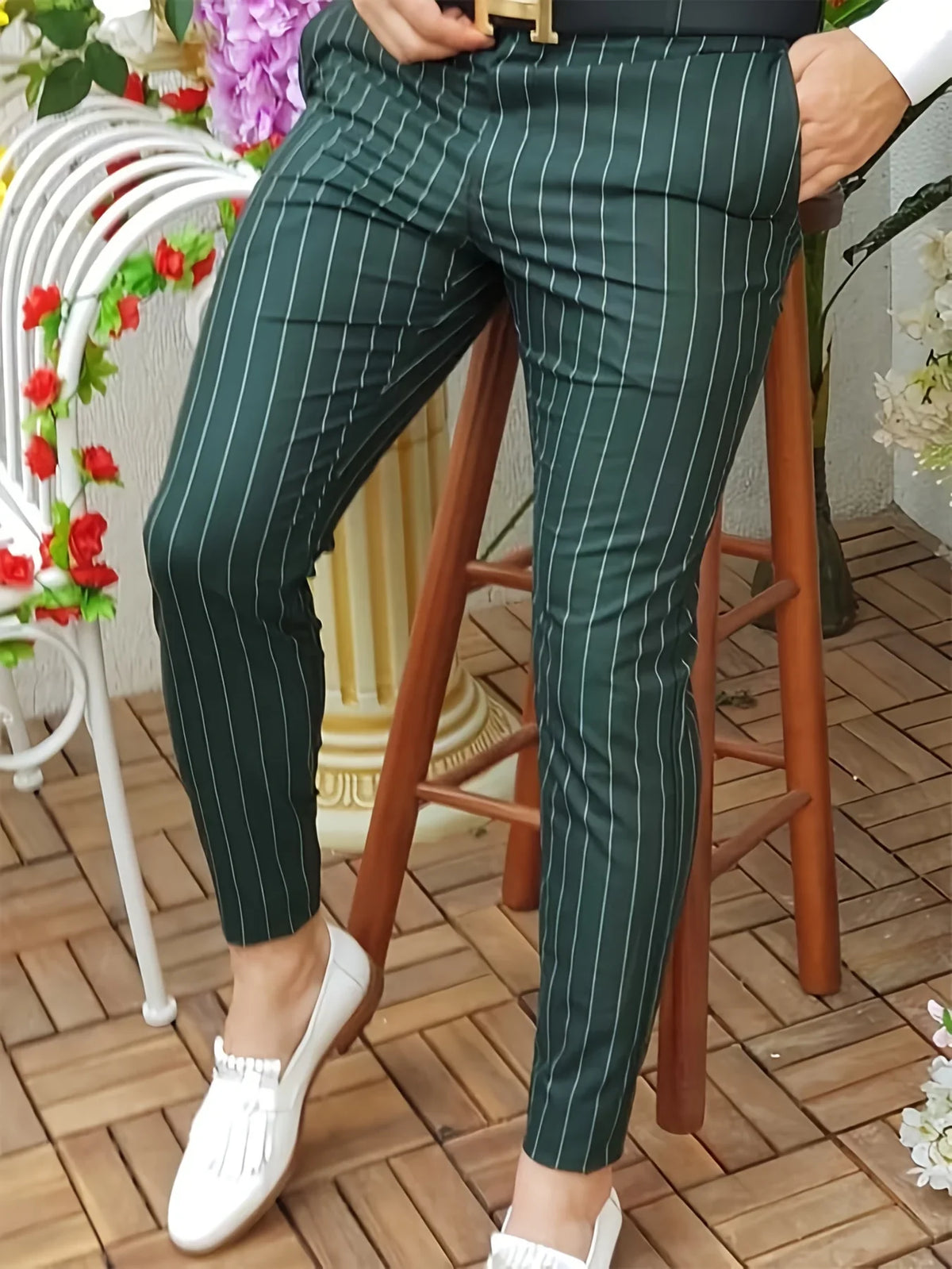 Slim-fit, green striped trousers with a flat front, worn casually with white loafers, showcasing a polished look.