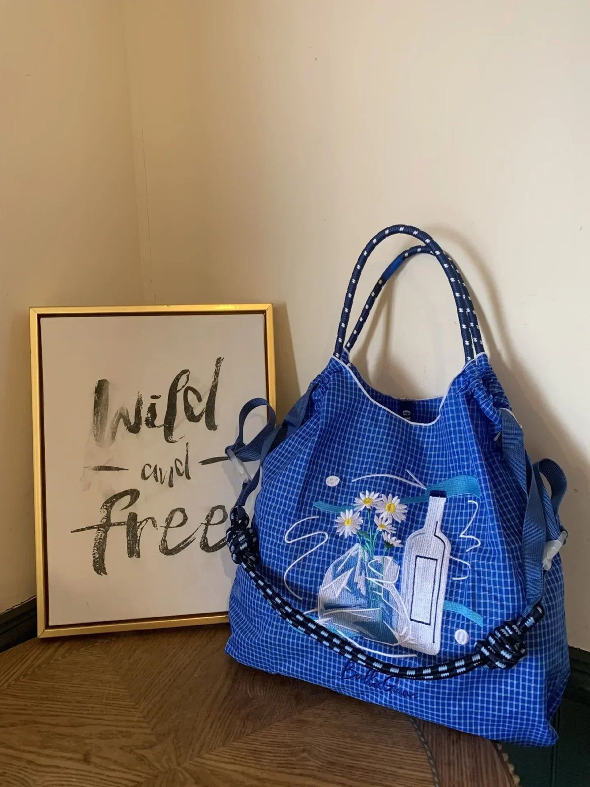 Lightweight blue nylon tote bag with floral embroidery and a bottle design, featuring two handles and a casual style.