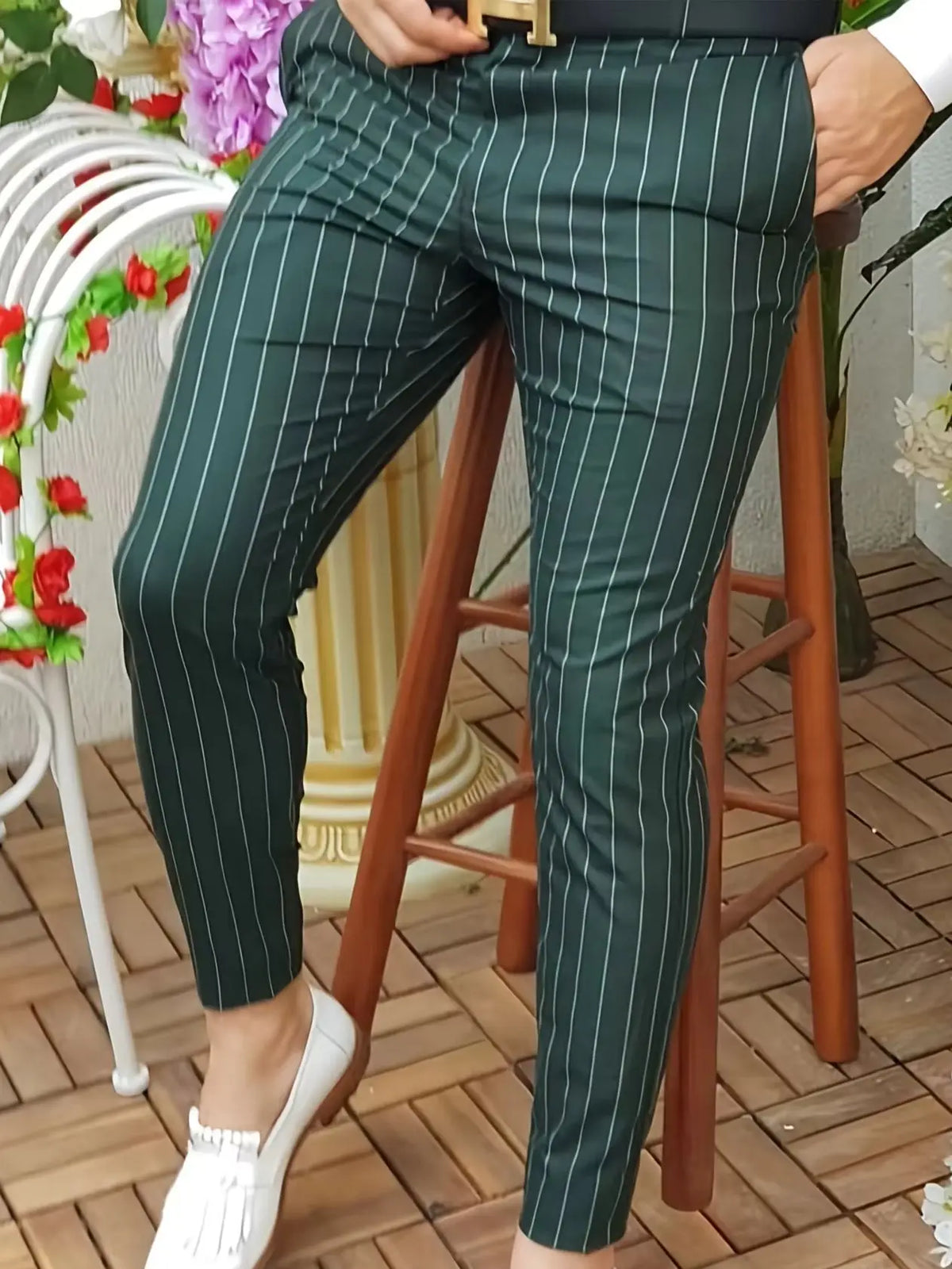 Slim-fit green striped trousers with a button fly, styled for casual wear. Paired with white loafers.
