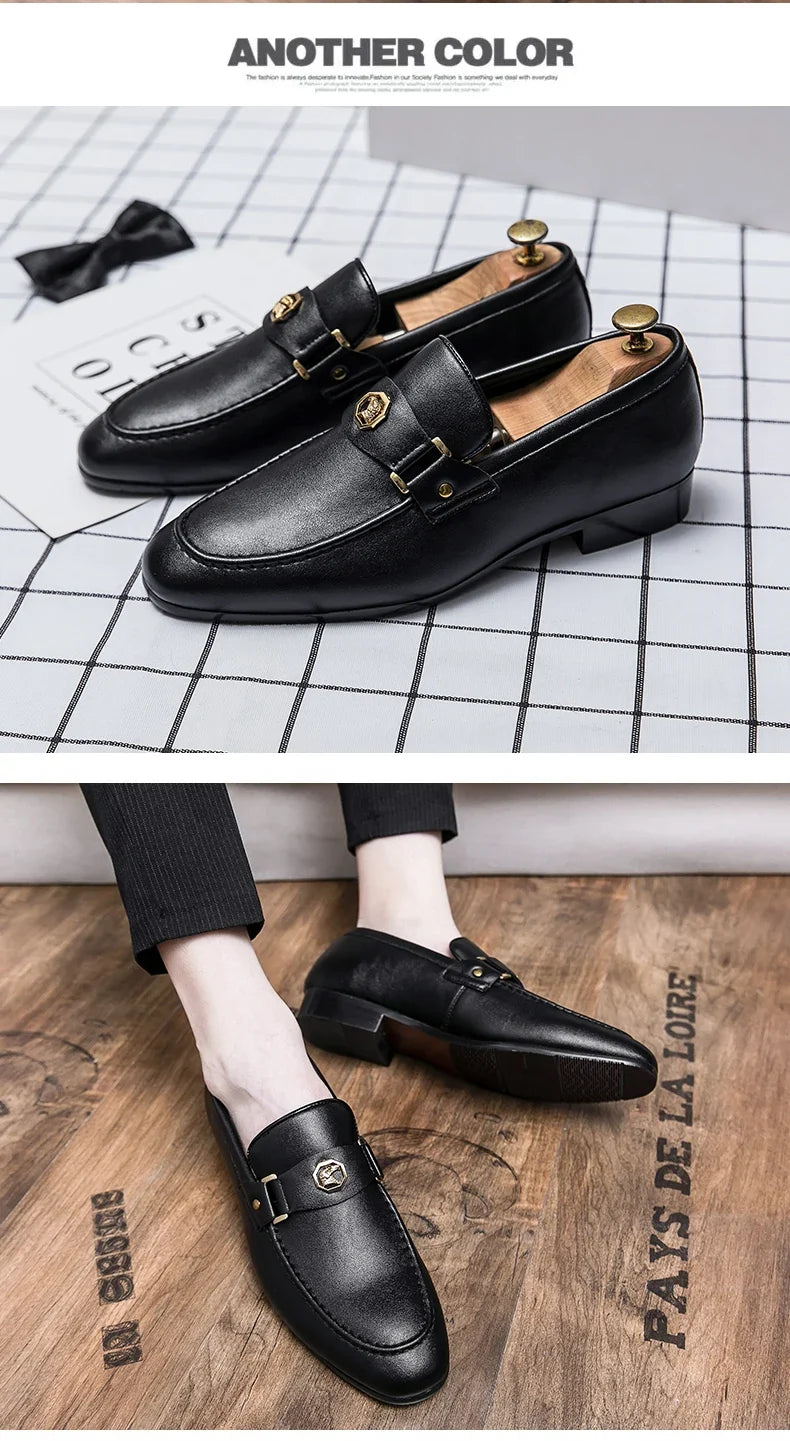 Black leather slip-on loafers with a round toe and metal buckle detail, styled with pinstriped pants.