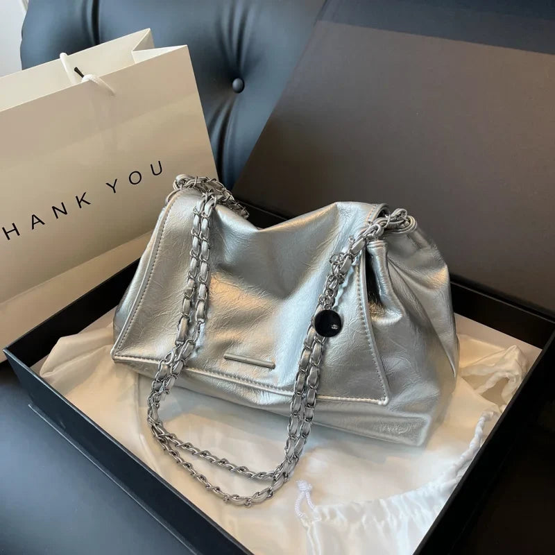 Silver handbag crafted from soft leather, featuring a chain shoulder strap and a stylish flap design.