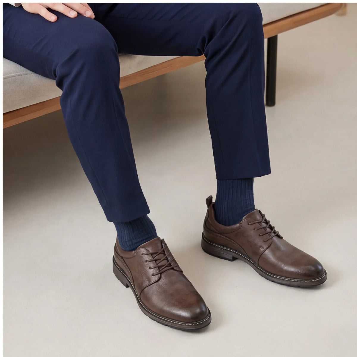 Brown Derby shoes with round toe, lace-up closure, worn with navy pants and matching socks. Rubber sole visible.