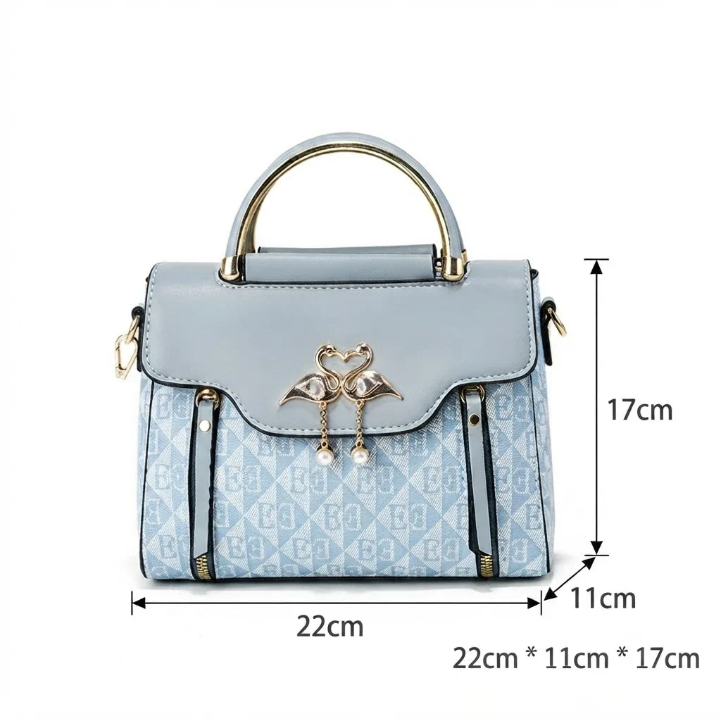 Light blue handbag with a structured design, featuring a gold handle and a decorative clasp with swan details.