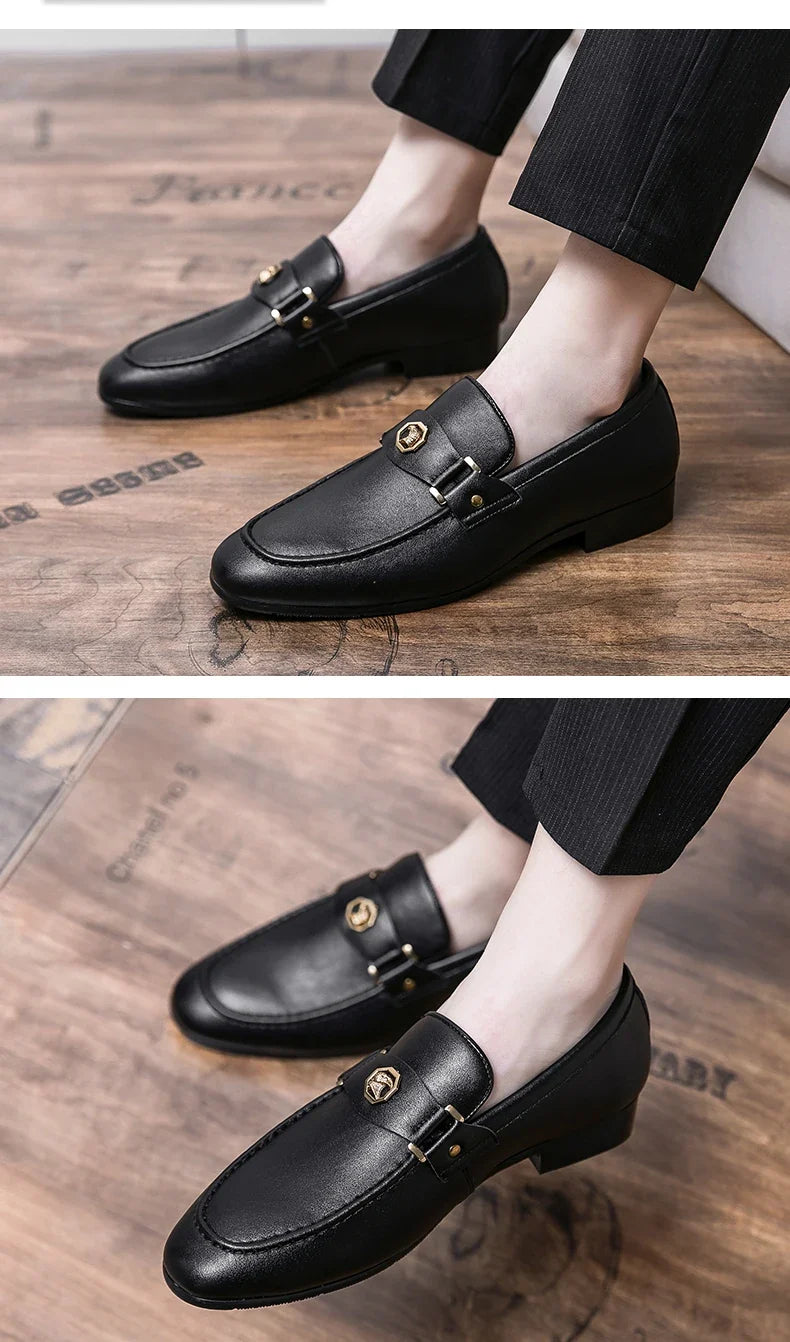 Black slip-on loafers for men featuring a round toe and gold metal buckle detail, styled with tailored pants.