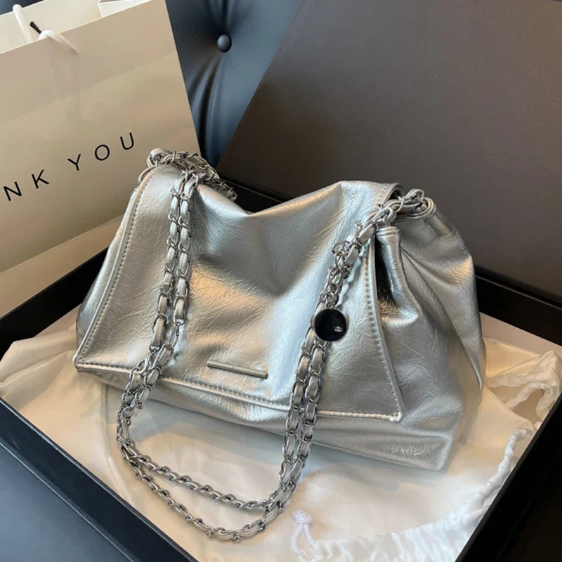 Large silver shoulder bag made of soft TPU leather, featuring a chain strap and a flap pocket.