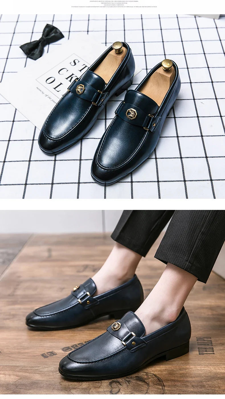 Men's elegant slip-on loafers in navy leather with a round toe and a gold metal buckle detailing, styled with fitted trousers.