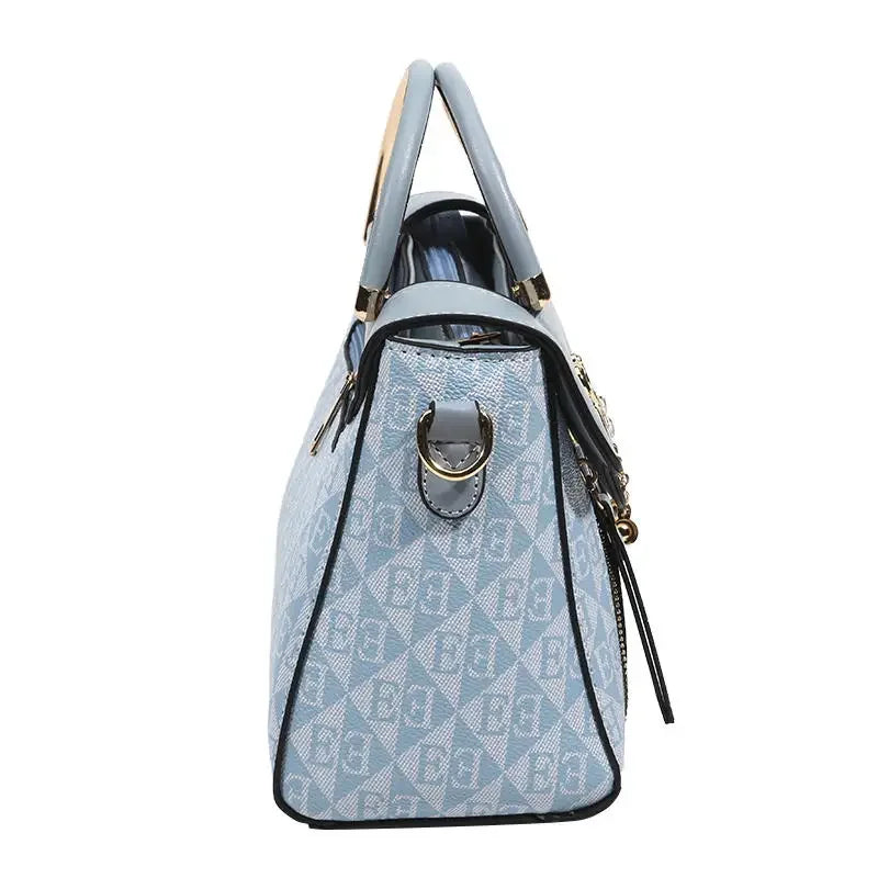 Light blue handbag with embossed geometric pattern, rectangular shape, dual handles, and detachable shoulder strap.