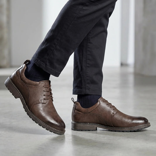 Brown lace-up derby shoes with a rubber sole, worn with dark pants and navy socks, showcasing a sleek and casual style.