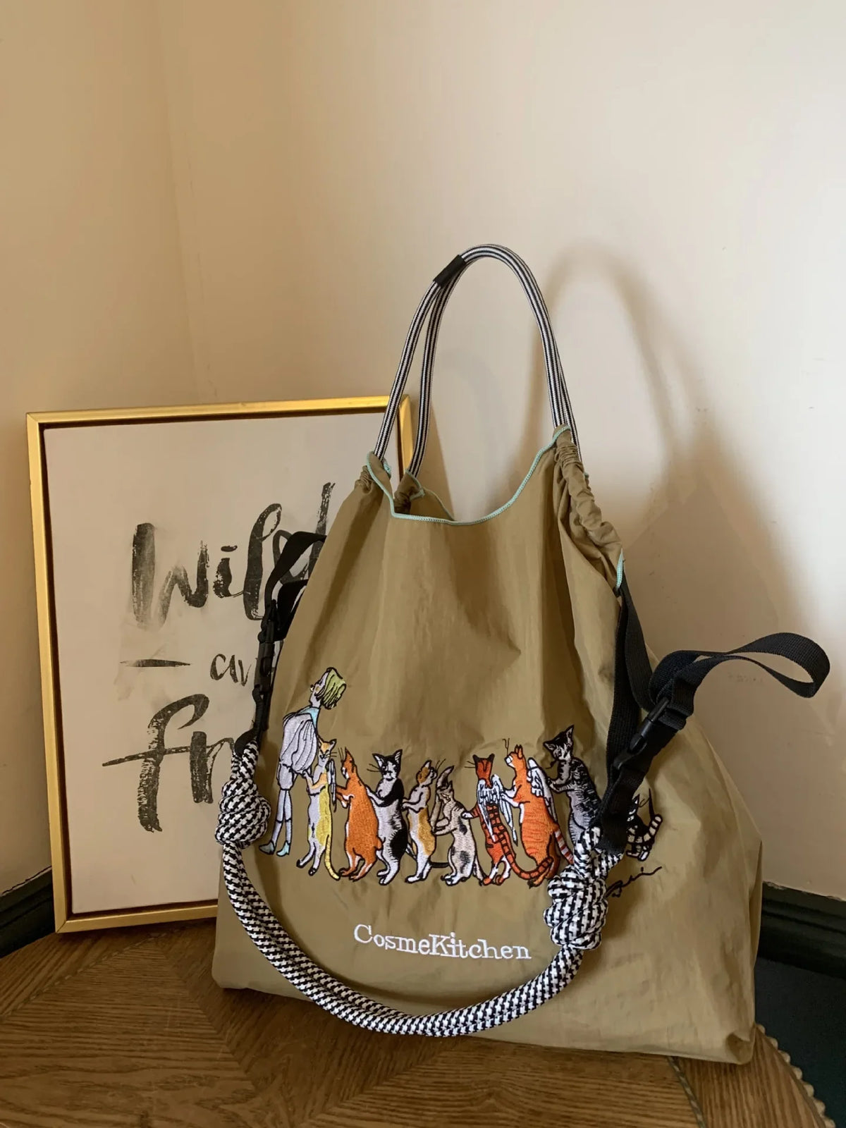 Lightweight olive green nylon tote bag with animal embroidery and a black and white patterned handle. Casual style, single-shoulder design.