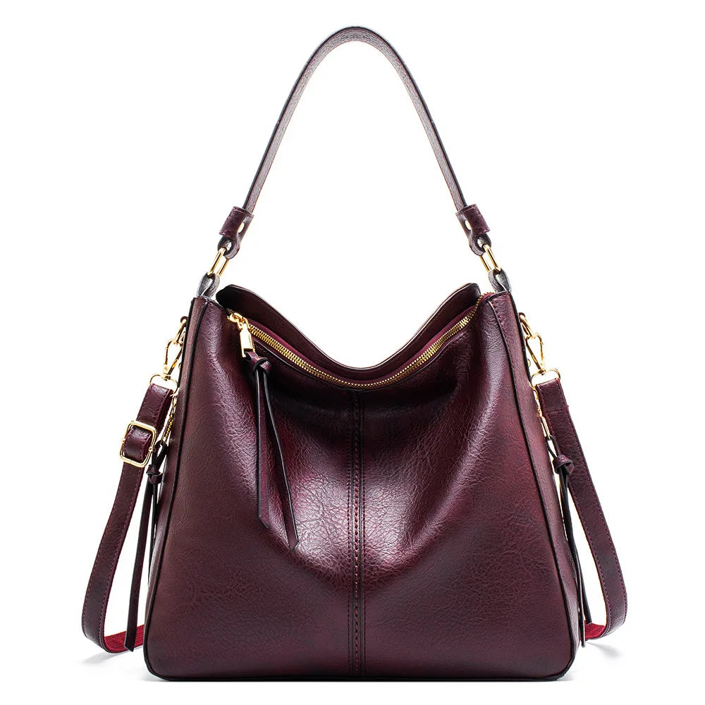Burgundy faux leather hobo handbag with a single shoulder strap and a zip closure, featuring a sleek, casual design.