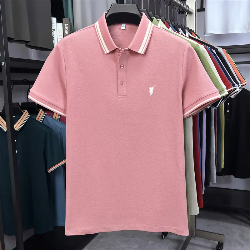 Short sleeve polo shirt in light pink with white pony embroidery and striped collar. Displayed against colorful shirts.