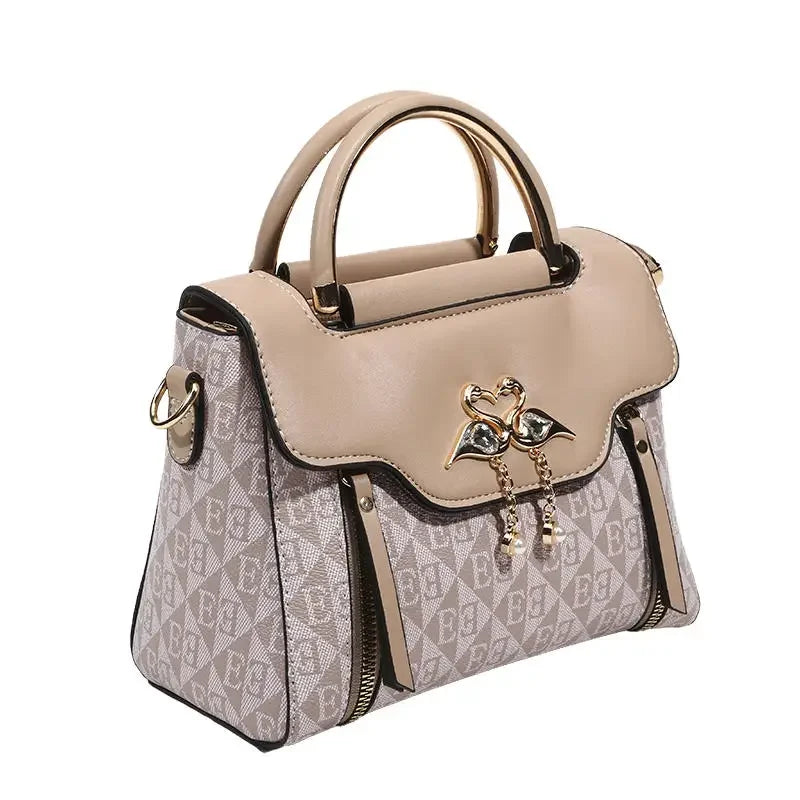 Beige and patterned handbag with gold detailing, soft material, features a top handle and removable shoulder strap.