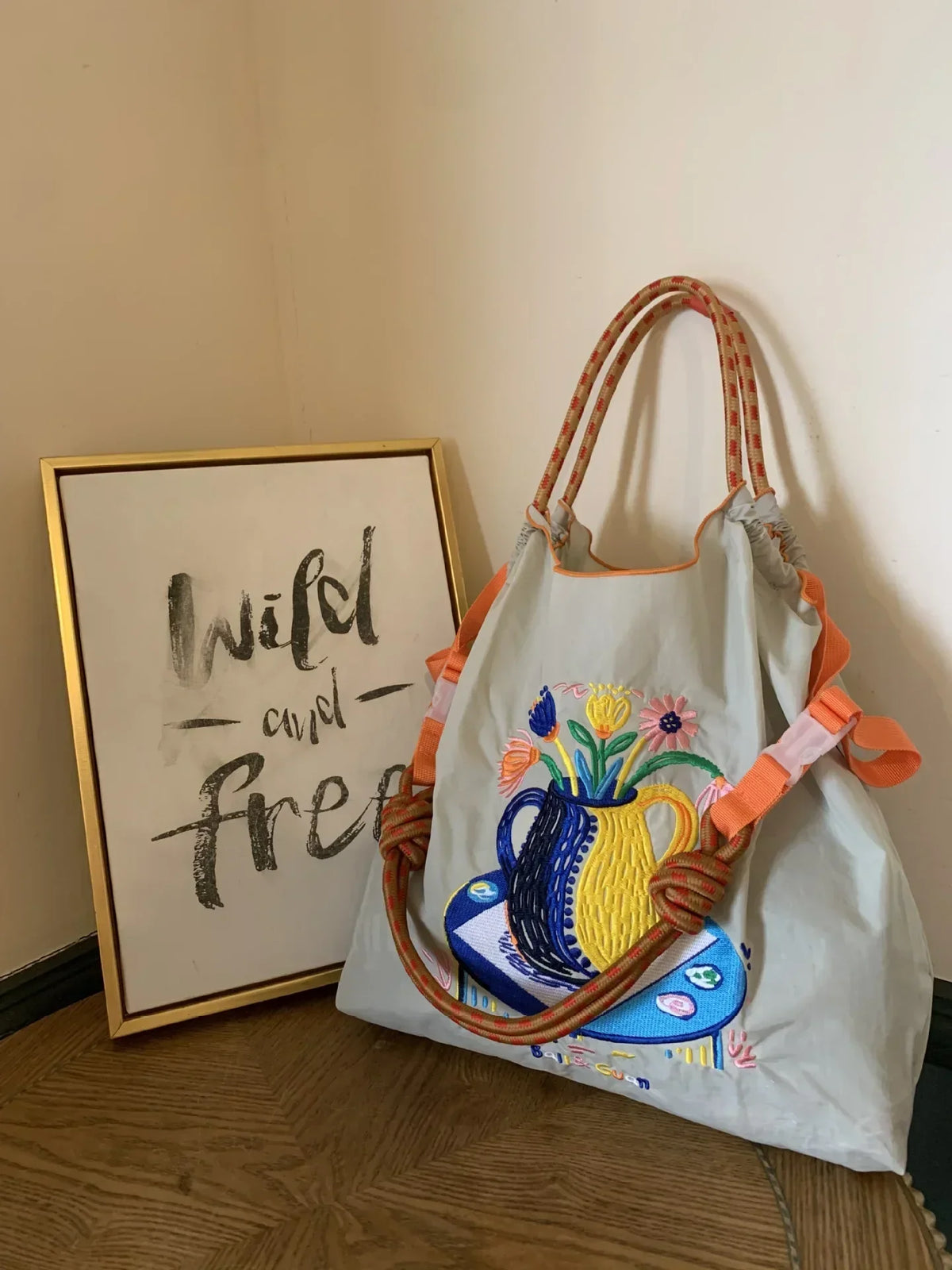 Lightweight grey nylon tote bag with colorful floral embroidery, featuring orange handles and a large-capacity design.