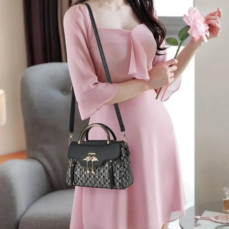 Versatile black and grey embossed handbag with a stylish handle and a detachable shoulder strap, worn casually with a pink dress.