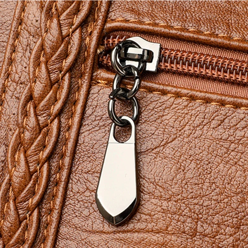 Brown leather handbag featuring a braided texture and a silver zipper pull chain detail.