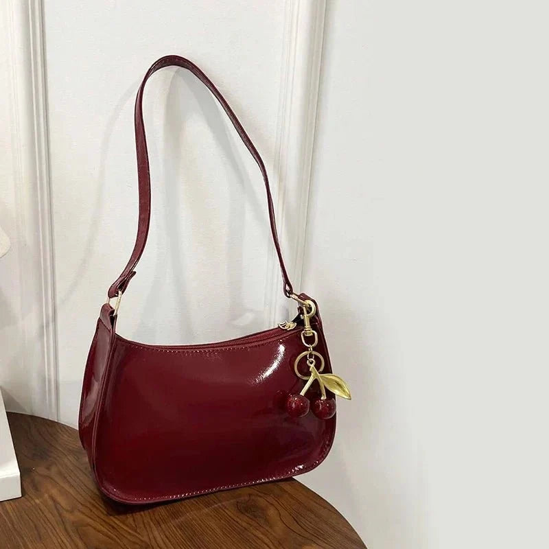 Women's pure leather cherry pendant handbag by TrendLux Wear, solid color, stylish leather handbag with cherry detail.