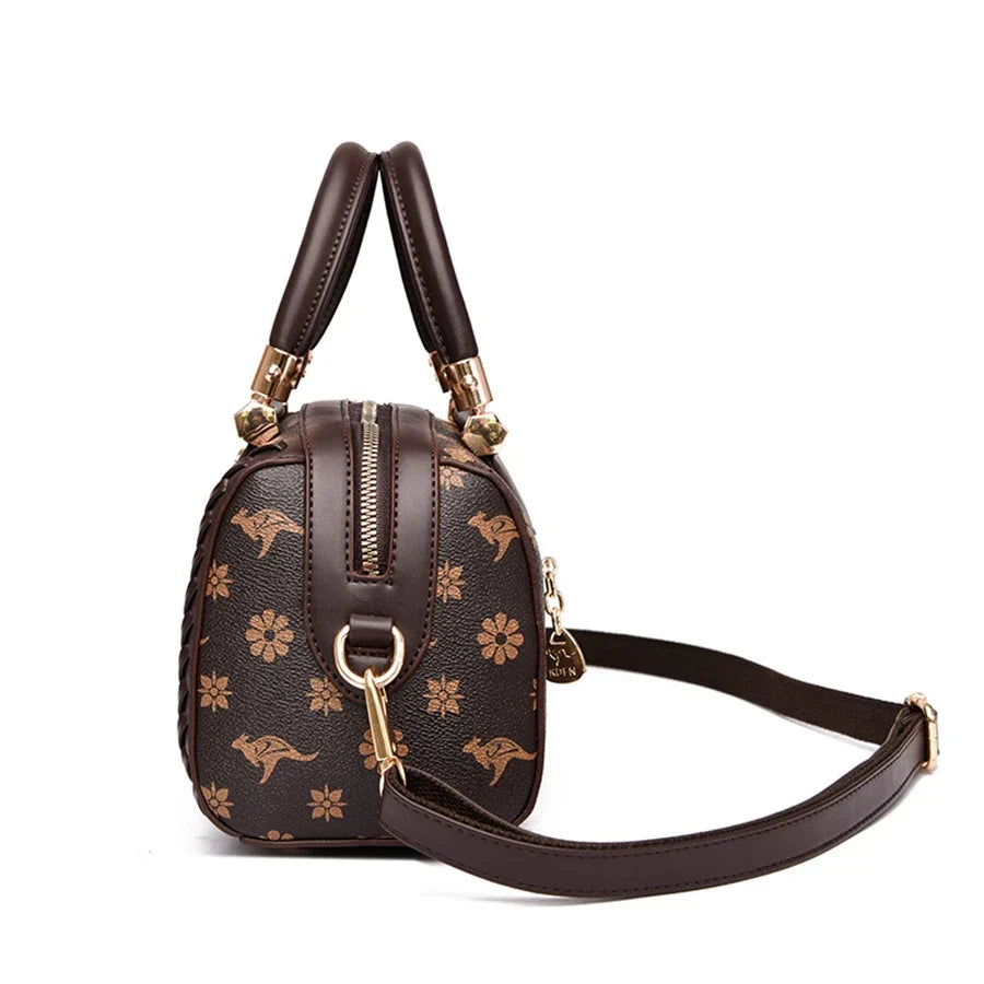 Brown shoulder handbag featuring a semi-woven design with gold animal and floral prints, adjustable strap, and zip closure.