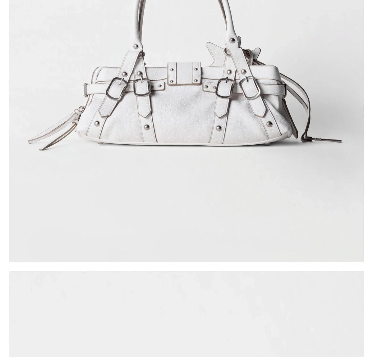 Rivet-embellished white handbag with adjustable crossbody strap and a stylish soft silhouette. Perfect for casual outings.