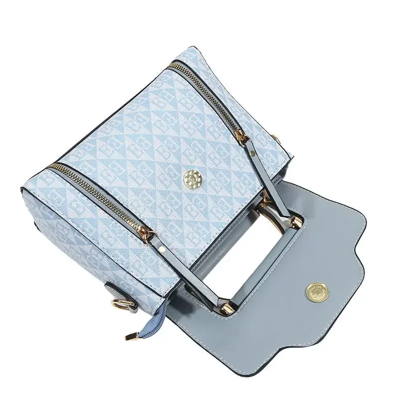 Light blue embroidered handbag with a rectangular shape, dual zippers, and a soft synthetic leather finish.