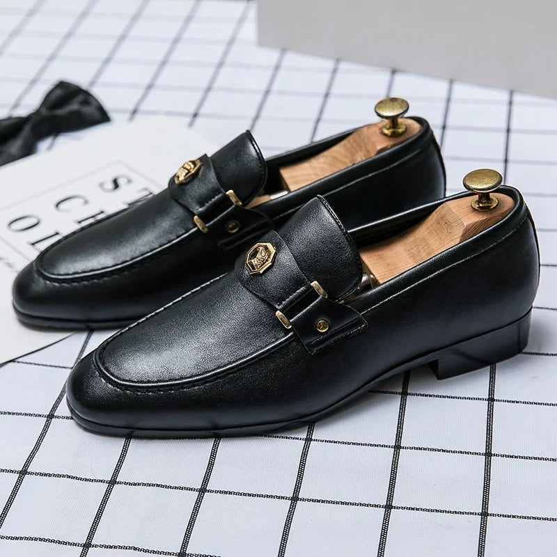 Elegant black leather loafers with a round toe, featuring a gold metal buckle detail, slip-on style.