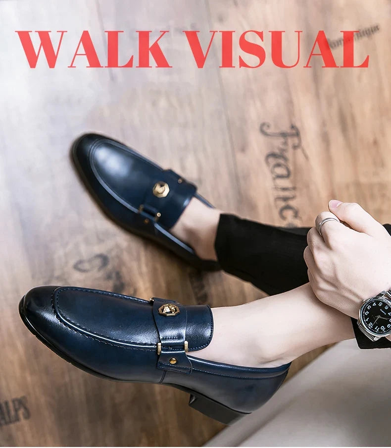Men's slip-on evening dress loafers in navy blue leather with a metal buckle detail, styled with black pants.
