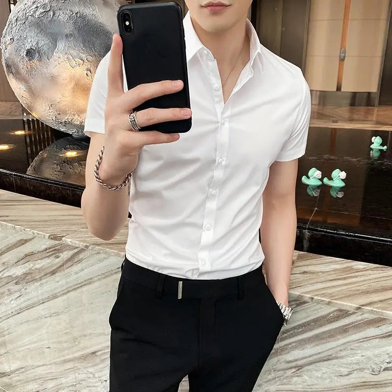 Short sleeve white dress shirt with a square collar, styled casually with black pants. The model poses with a phone.