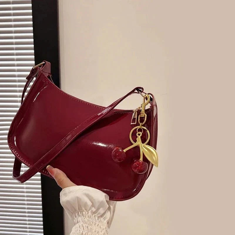 Women's pure leather cherry pendant handbag by TrendLux Wear, solid color with stylish cherry charm and functional shoulder strap.