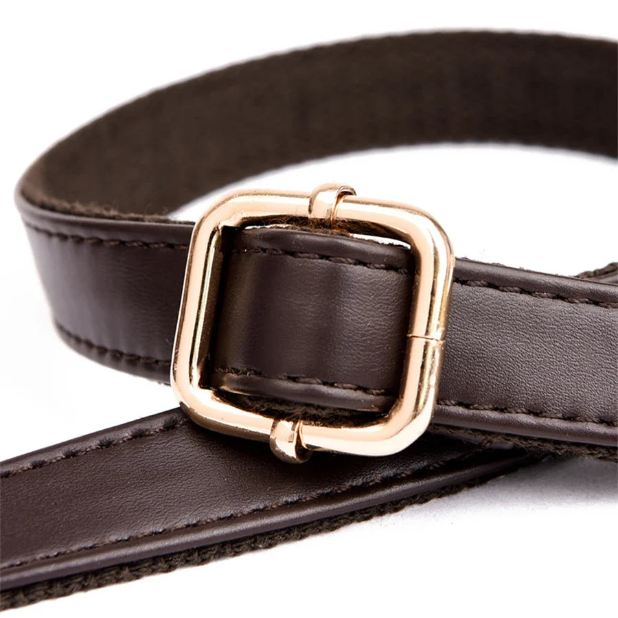 Close-up of a brown leather shoulder strap featuring a gold square buckle and sturdy stitching for durability.