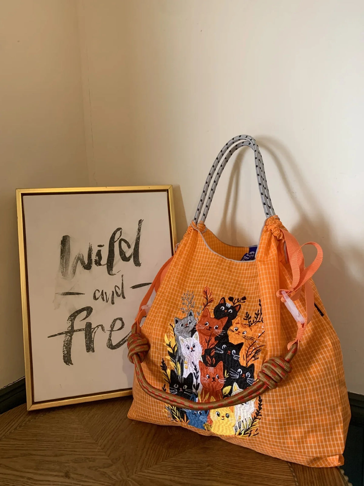 Large orange tote bag with embroidered cats, featuring dual handles with knotted details and a casual, lightweight style.