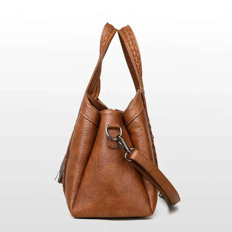 Brown leather shoulder bag with braided straps, soft texture, crossbody option, and two handles for versatile carrying.