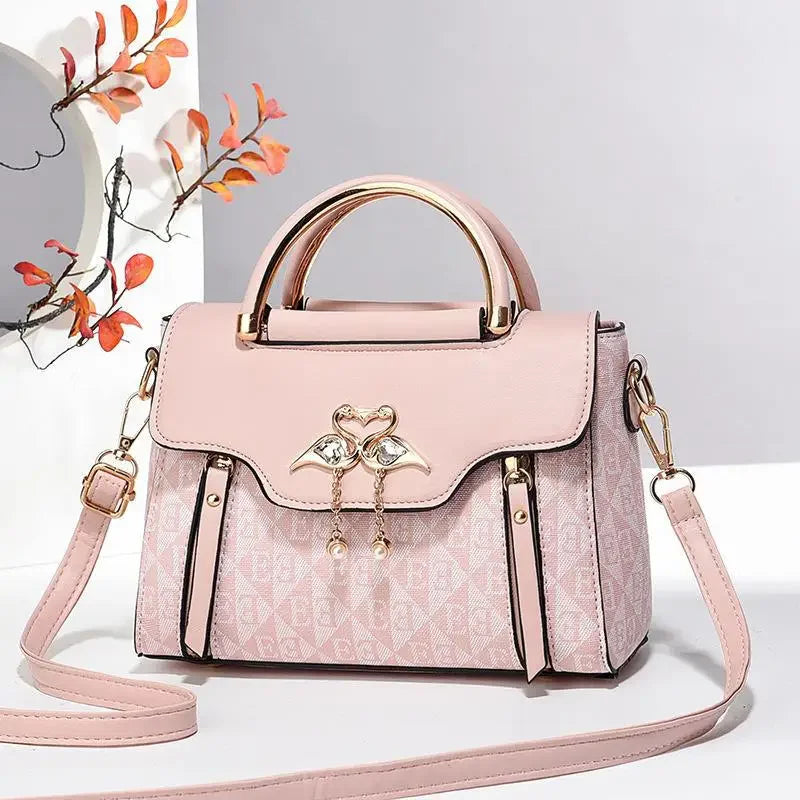 Stylish pink handbag featuring a unique heart and wing embellishment, shoulder strap, and a structured design.