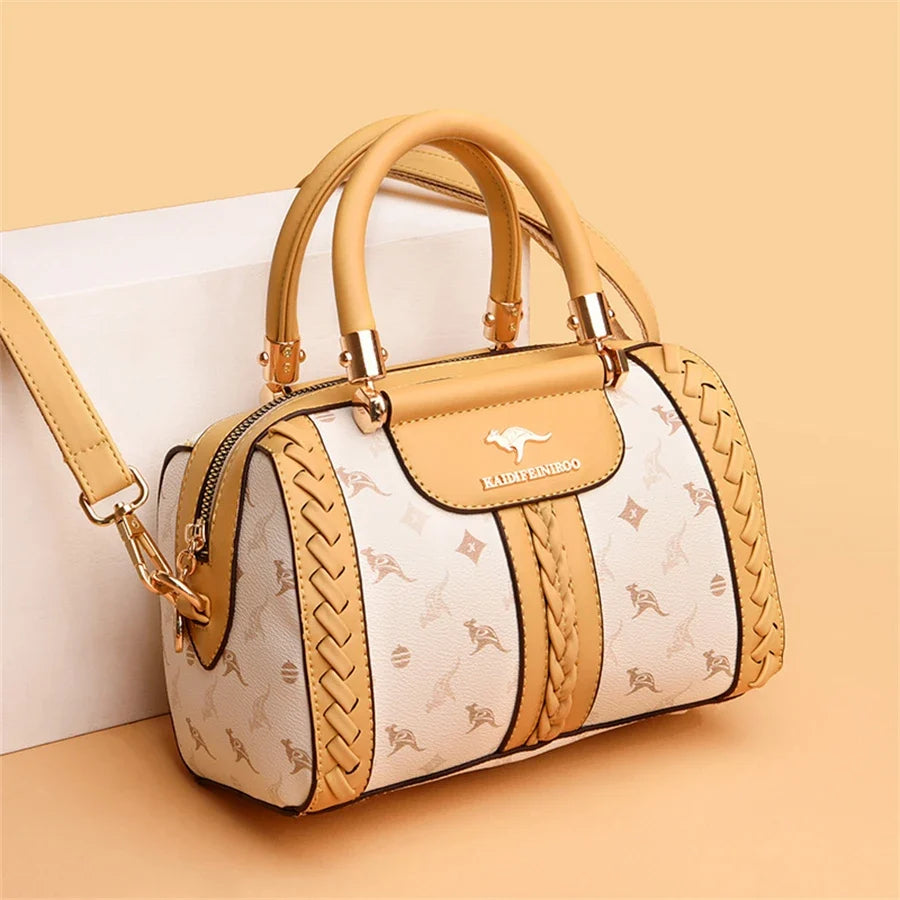 Luxury handbag in cream and tan with a braided design, gold accents, and a zip closure, featuring an adjustable shoulder strap.