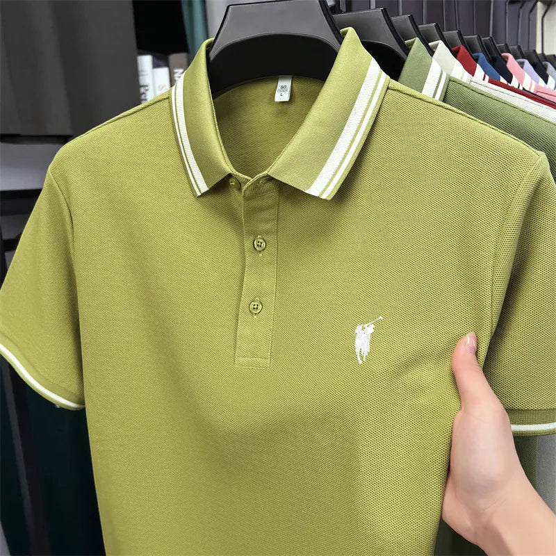 Short sleeve polo shirt in olive green with white striped collar and embroidered logo, held by a hand. Casual summer wear.